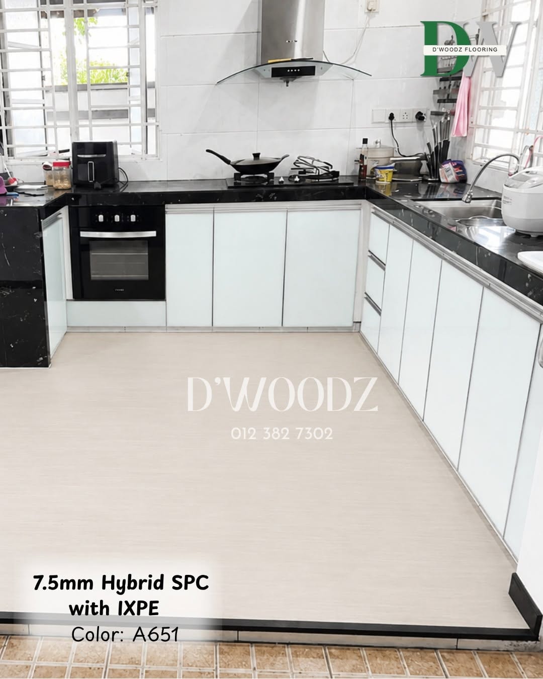 A kitchen with white cabinets, a black worktop and a hob, on a pale plank floor; the D'Woodz watermark and product label in frame.